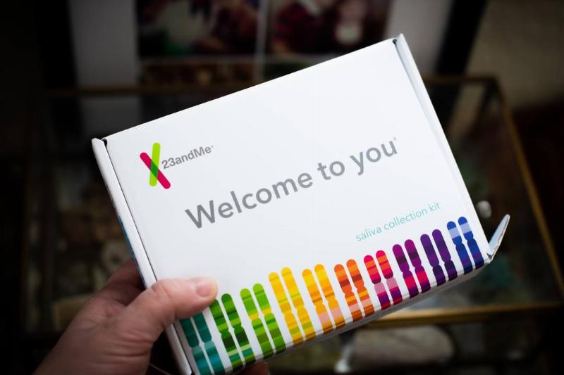 A person holds a 23andMe DNA testing kit.