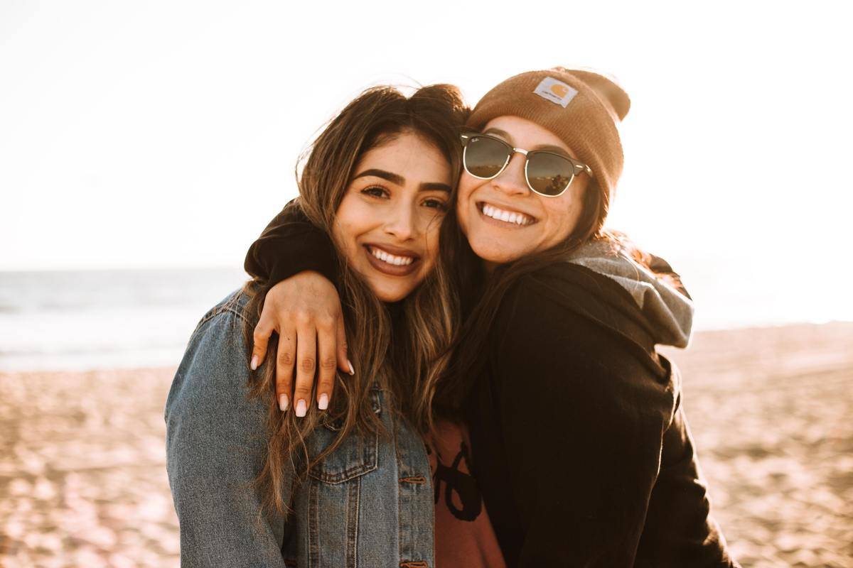 Two friends pose on the beach together.
