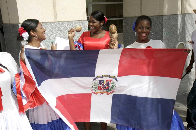 Women hold a Dominican Republic flag at the Miami Book Fair International parade.