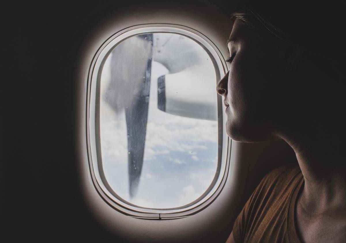 A woman looks out a plane window.