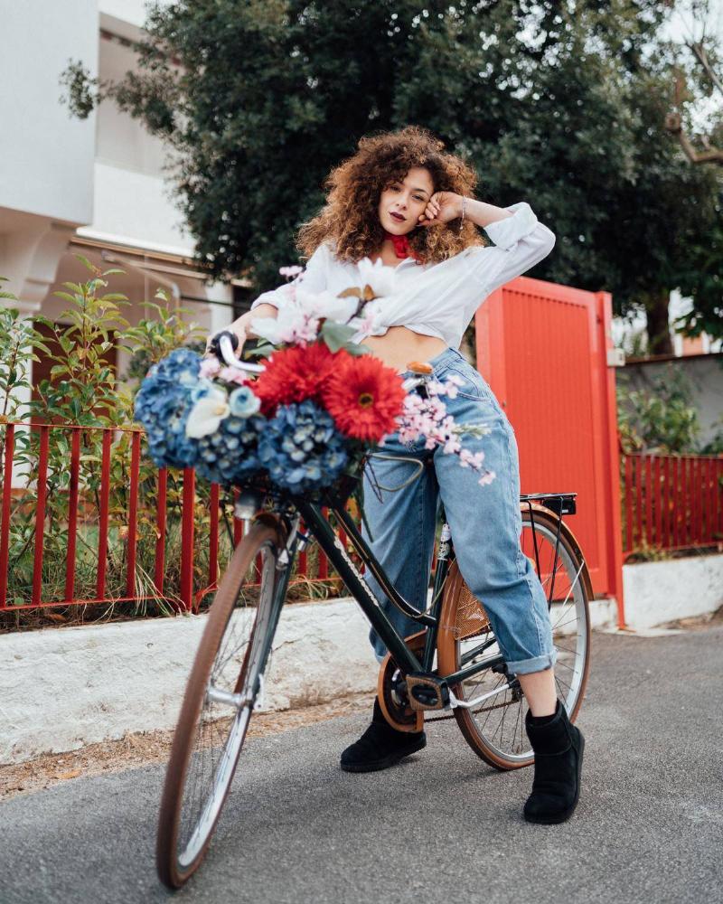 woman standing next to a bike that has flowers on it 