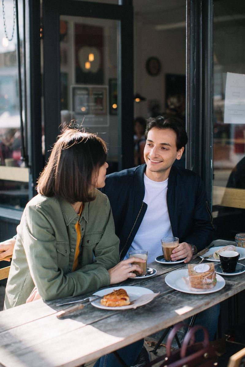 man and woman sitting outside at a coffee shop having coffee
