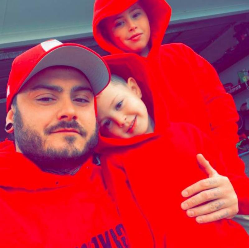 Jake James posing with two young kids all wearing red