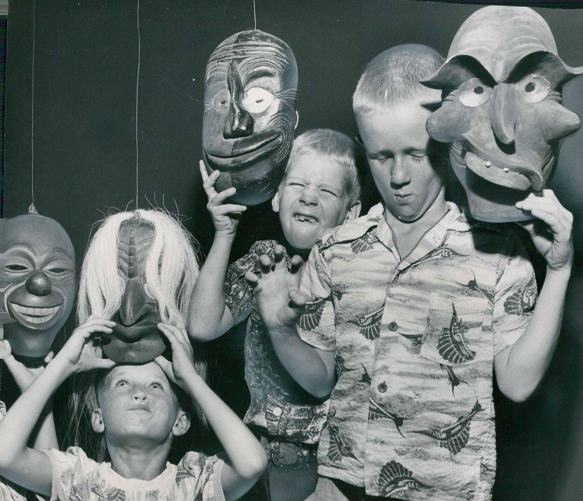 A photo from 1952 of children trying to emulate the faces of the masks they're holding on Halloween