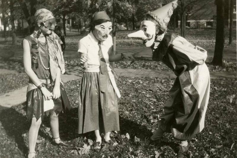 Three girls wearing masks and in costume stand outside and converse with each other