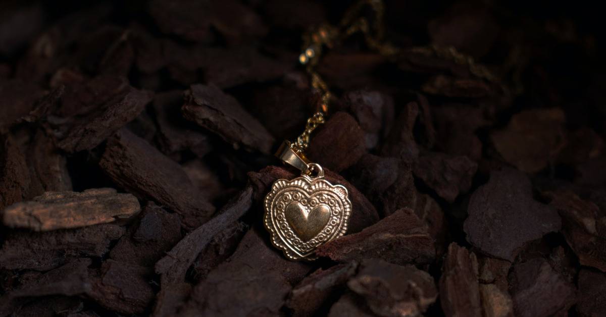 A heart-shaped locket laid on rocks.