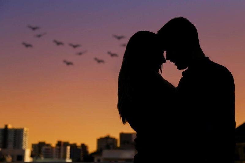 A silhouette of a man and woman kissing at sunset 