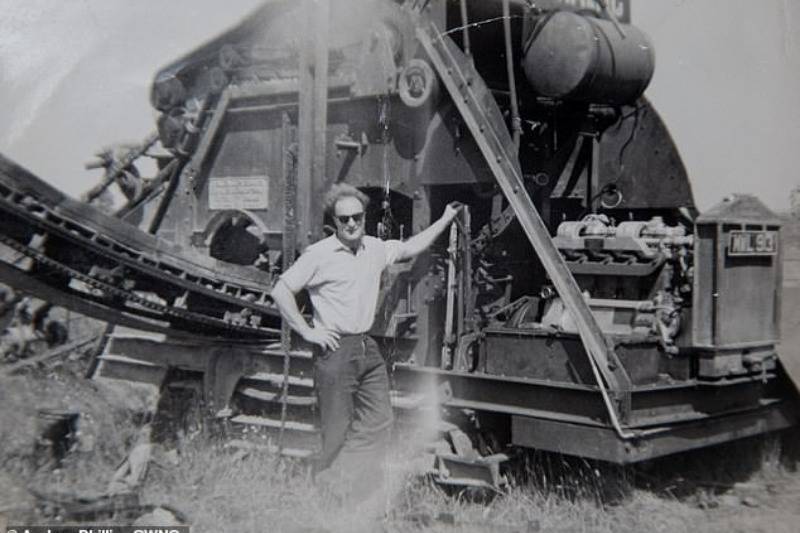 husband posing beside train structure vintage photo