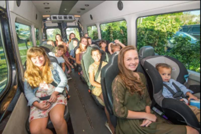 all kids sitting on a bus smiling for the camera