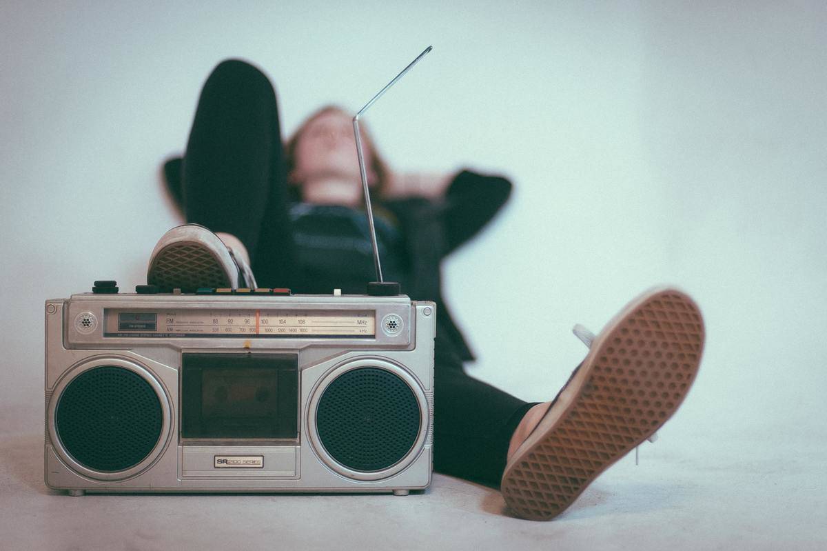 laying down woman with foot on the stereo listening to music