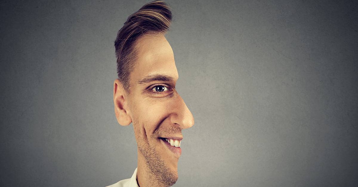 man's half face on grey background smiling