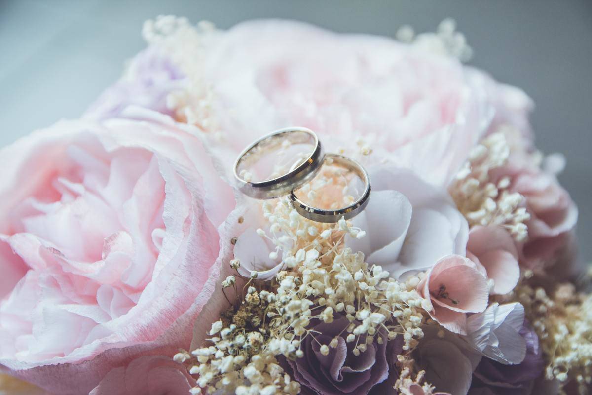 wedding bands over pink bouquet