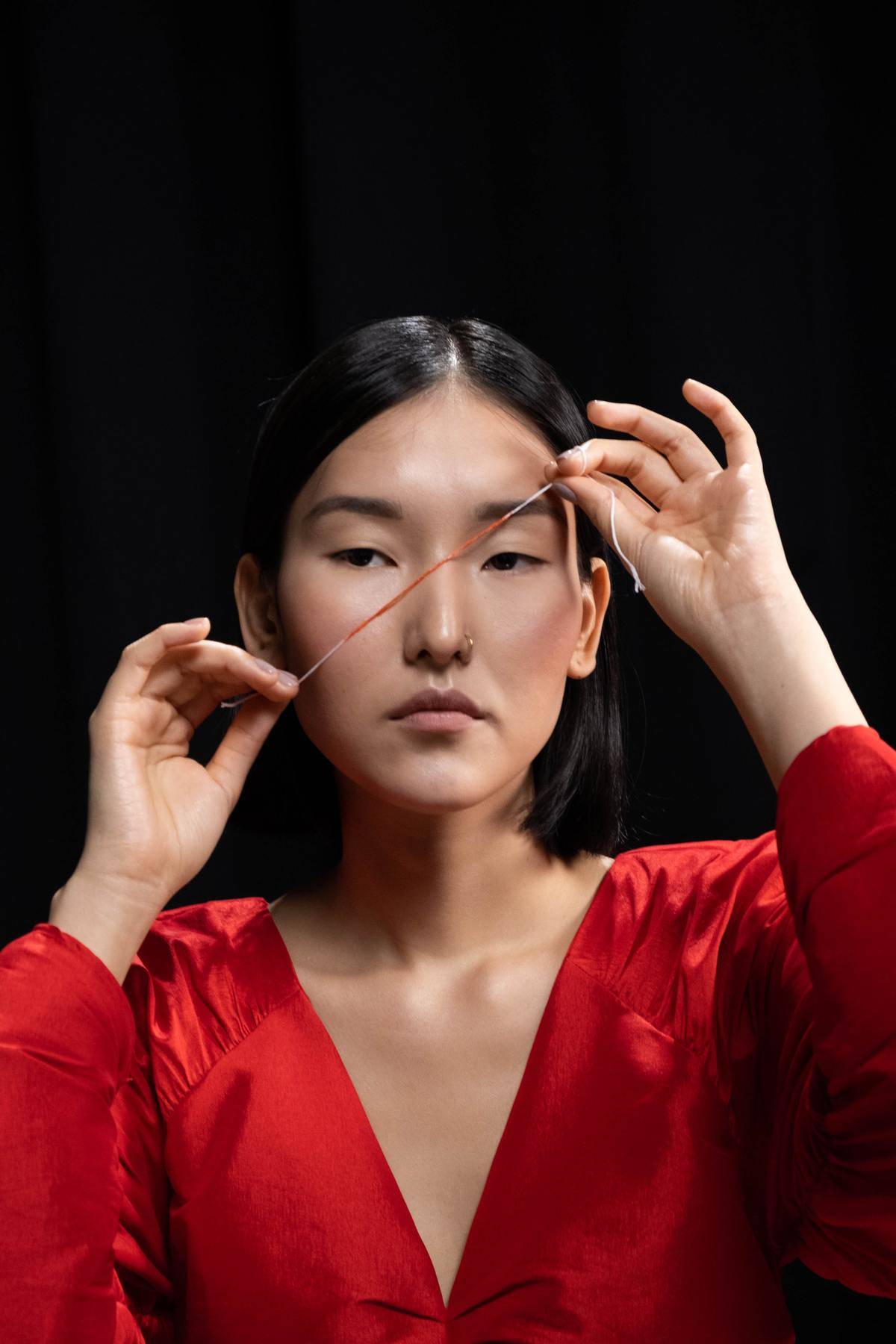 woman holds red string by her face