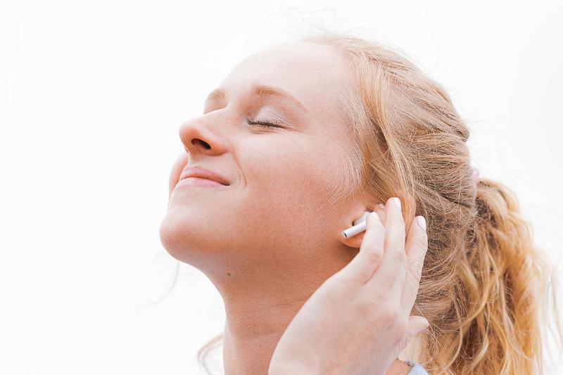 woman listening to music in earpod with eyes closed