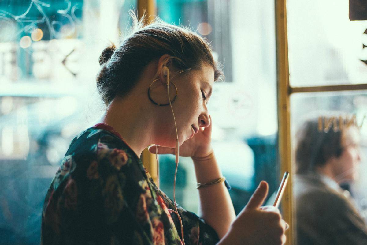 woman listens to music from her phone through earphones on the bus