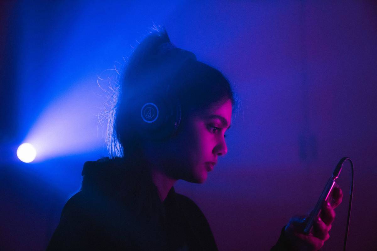 woman with headphones in purple lighting listening to music