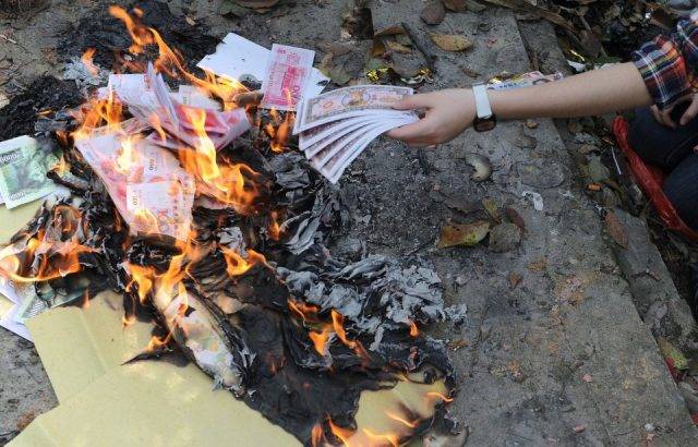 A Chinese woman burns paper money at a grave on Qingming, a day to honor the dead.