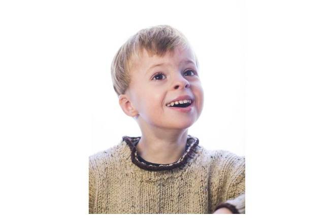 A young boy smiling with his teeth.