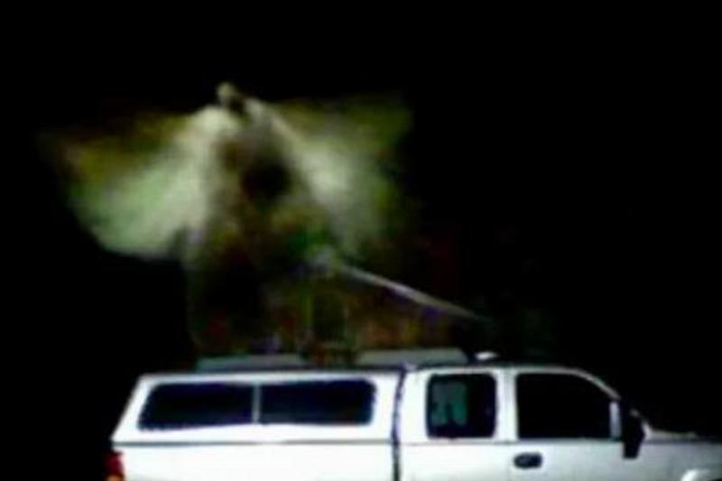 Angel A blurry figure on top of a white truck that looks like an angel