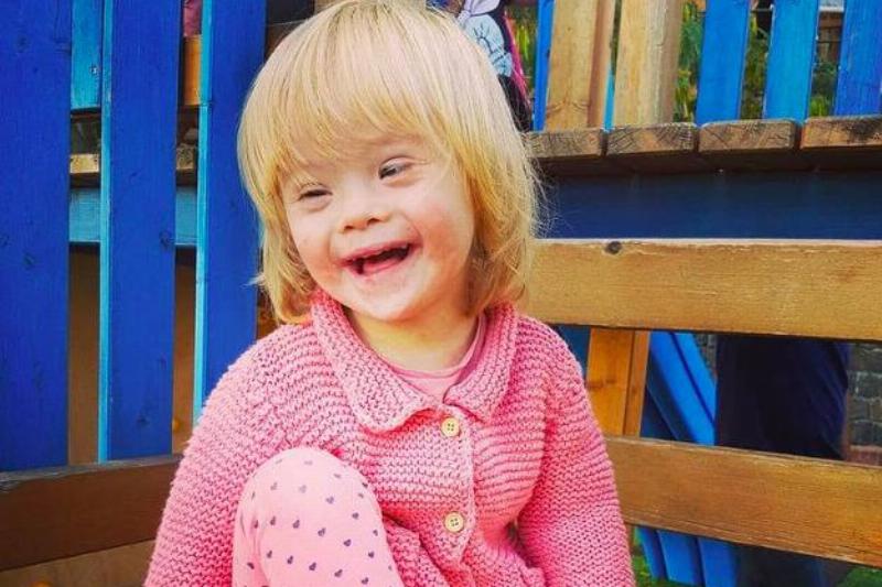 A little girl with down syndrome smiling at the camera