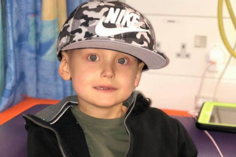 A little boy wearing an oversized Nike hat, smiling at the camera.