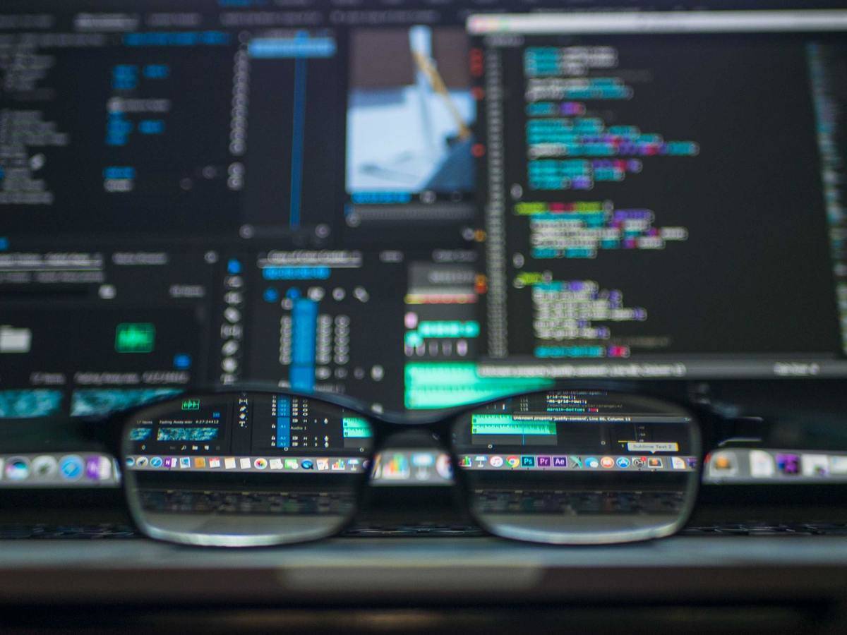 Glasses placed in front of a computer screen with coding on it.