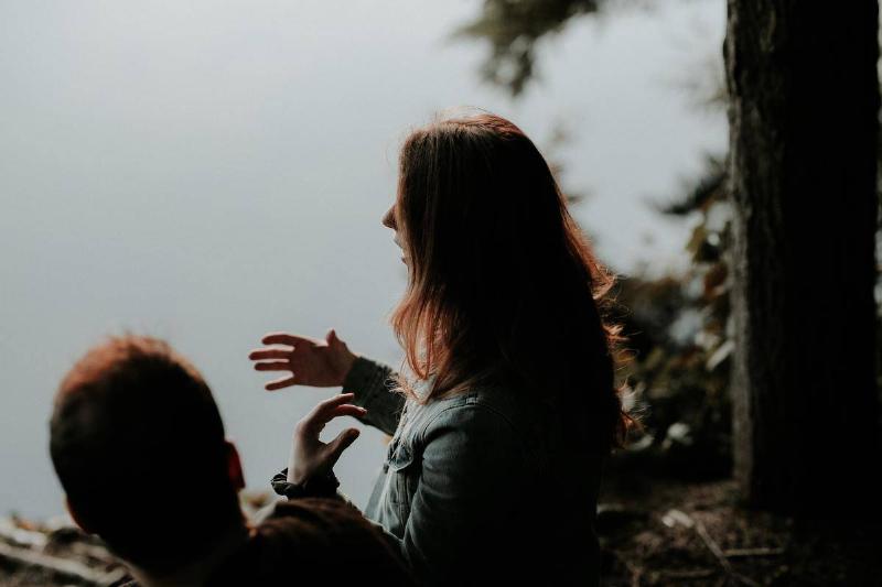 A man and a woman talking in a forest.