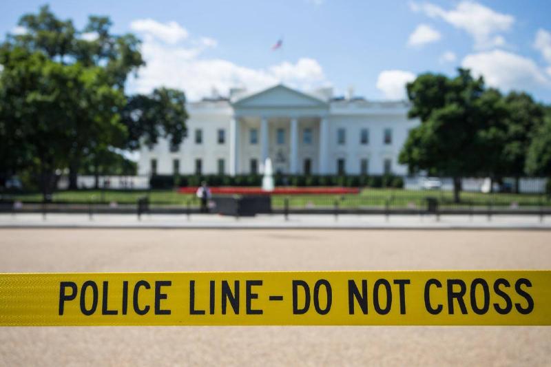 A blurred image of the White House with a focus on caution tape that reads 