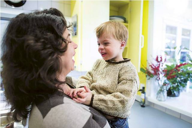 A mother holding her young son, smiling at each other.