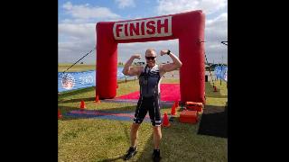 A man flexing his muscles at a finish line.