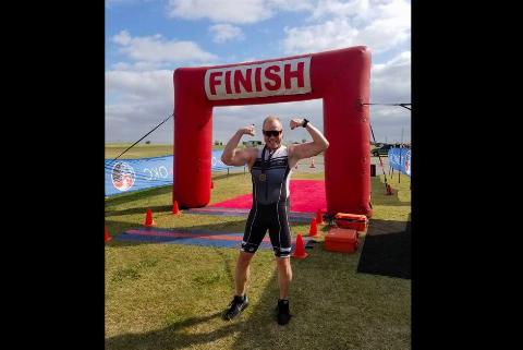 A man flexing his muscles at a finish line.