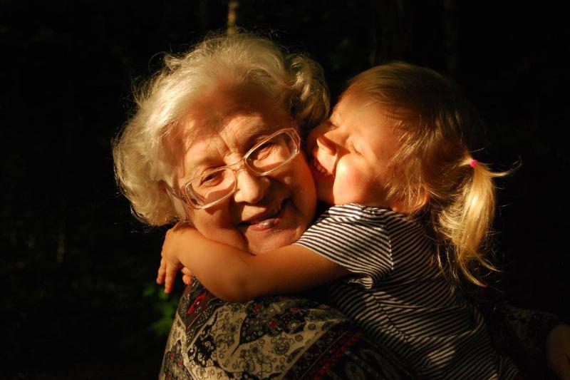An elderly woman and a small girl hugging.