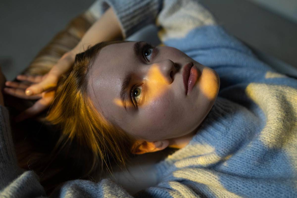 /woman-in-blue-sweater-lying-on-bed