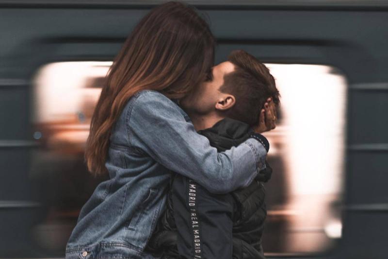 man and woman kissing by moving train as he carries her by the elgs