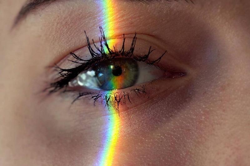 rainbow reflection over close up of green eye