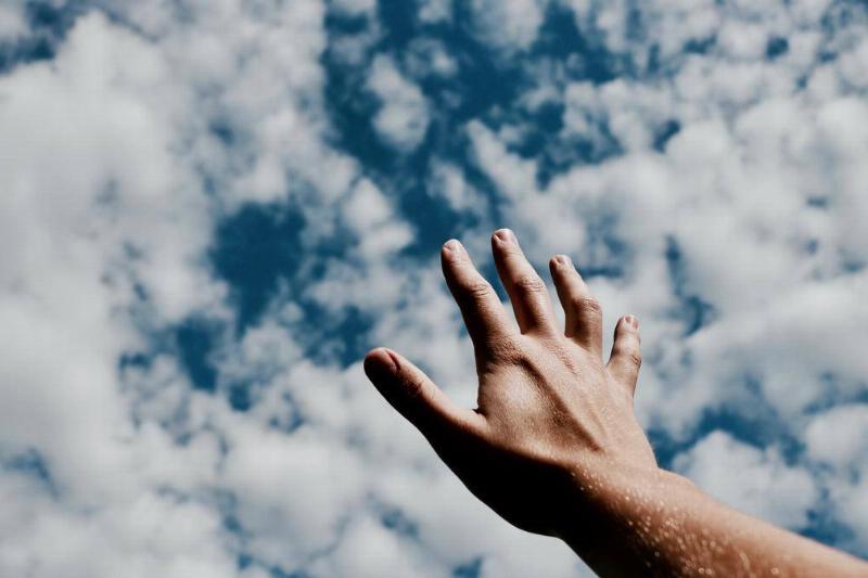 An open hand reaching into the clouds.