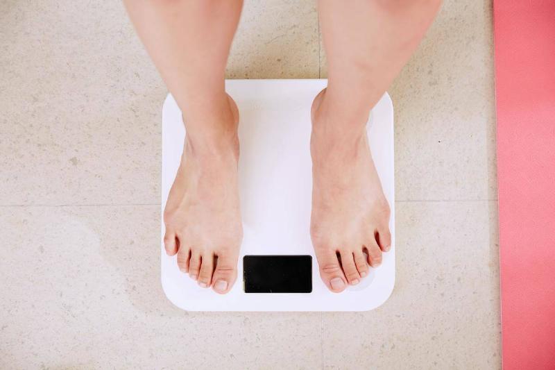 Scale A person standing on a white scale, barefoot.