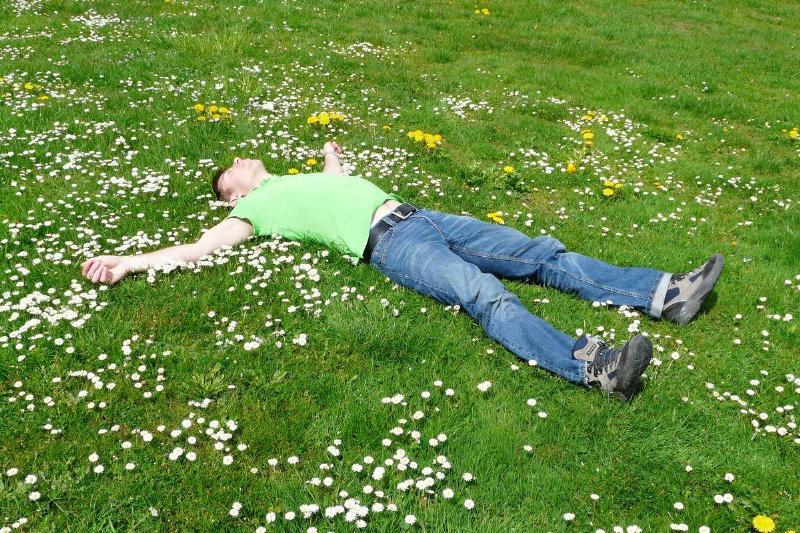 A man sleeping on his back in an open field.