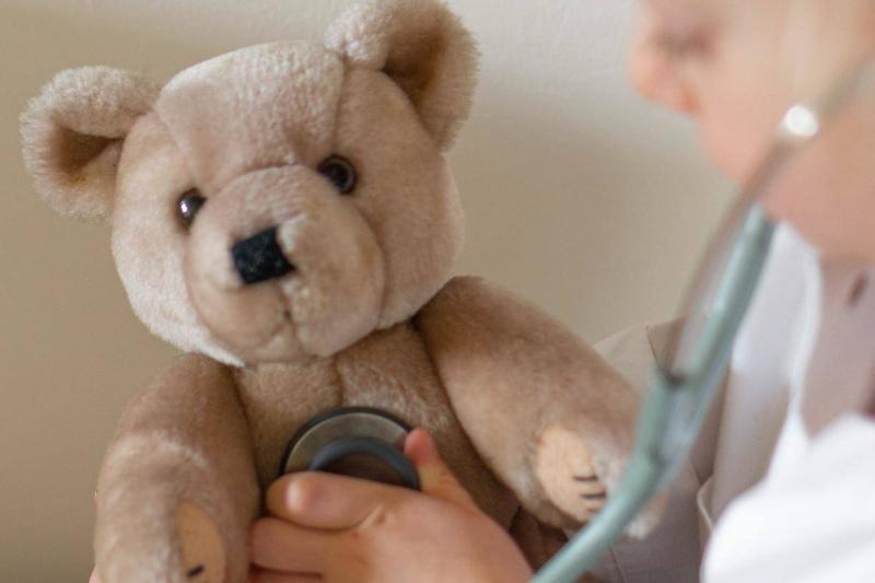 A stethoscope is held up to a teddy bear's stomach.