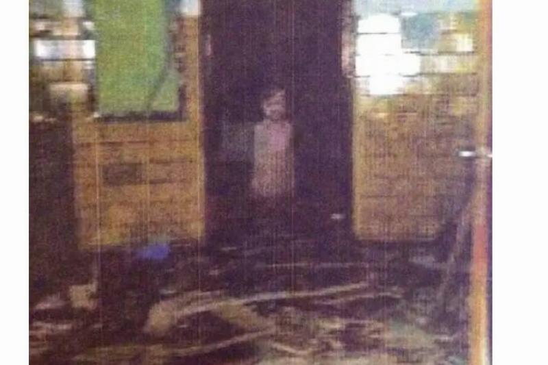 A ghostly figure of a little boy standing in an abandoned school.
