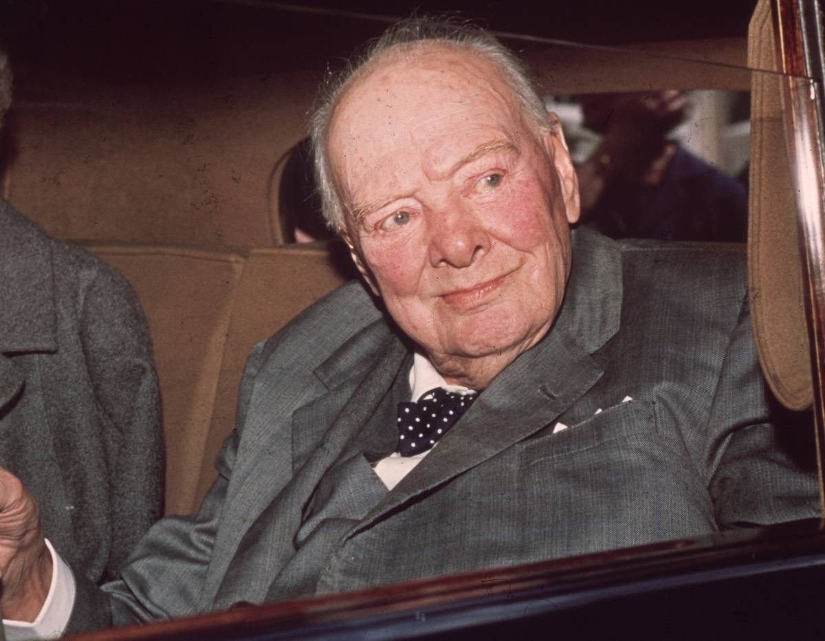 President Winston Churchill looking out a car window, wearing a grey suit.