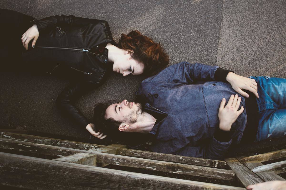 couple laying on the floor shoulder to shoulder looking at each other