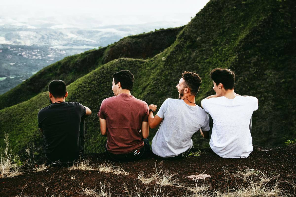 guy friends laughing while sitting on edge of mountain