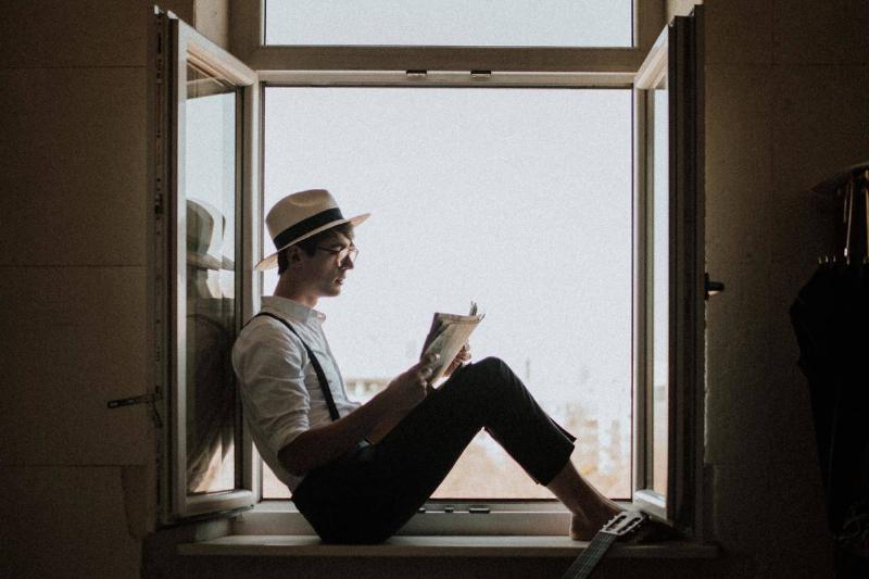 man sitting at window reading