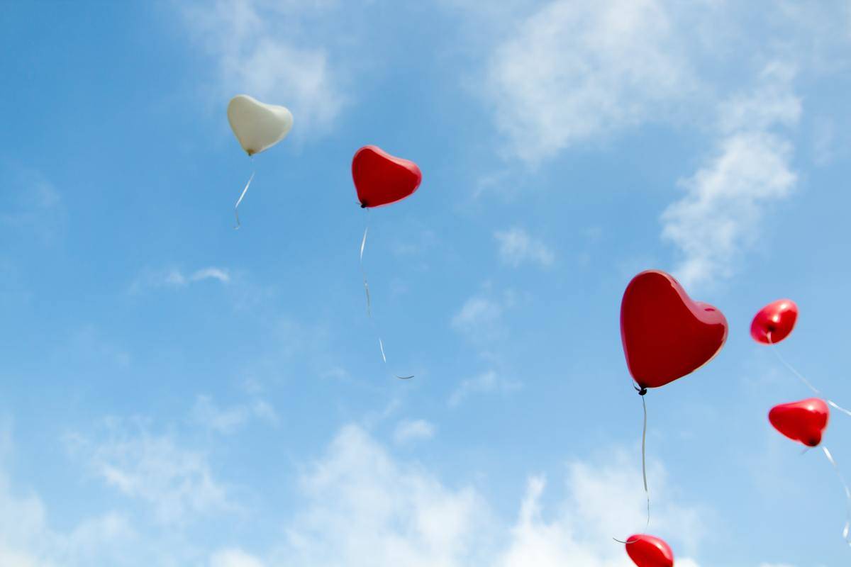 red heart-shaped balloons flying in the sky