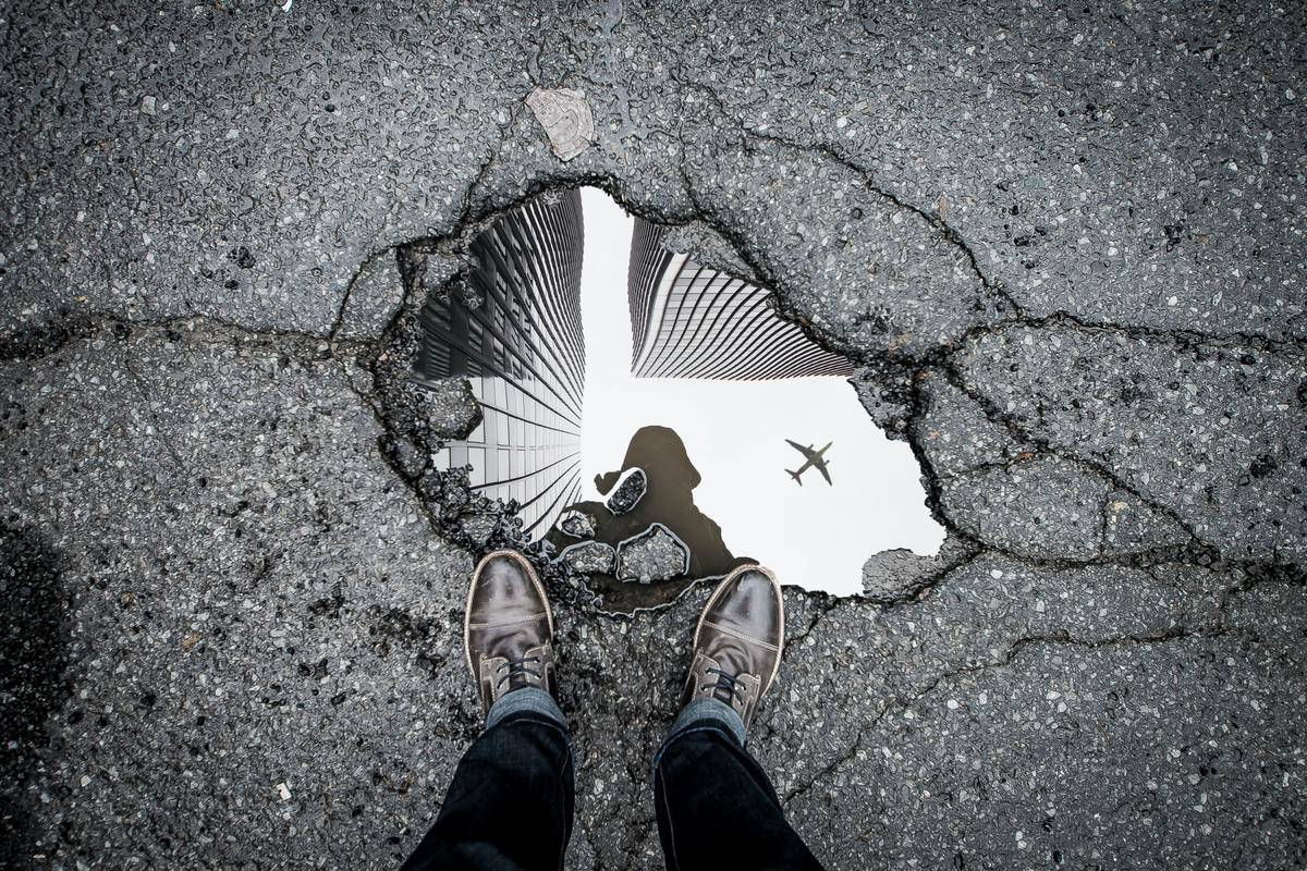 close up of man's shoes standig by vague reflection in puddle