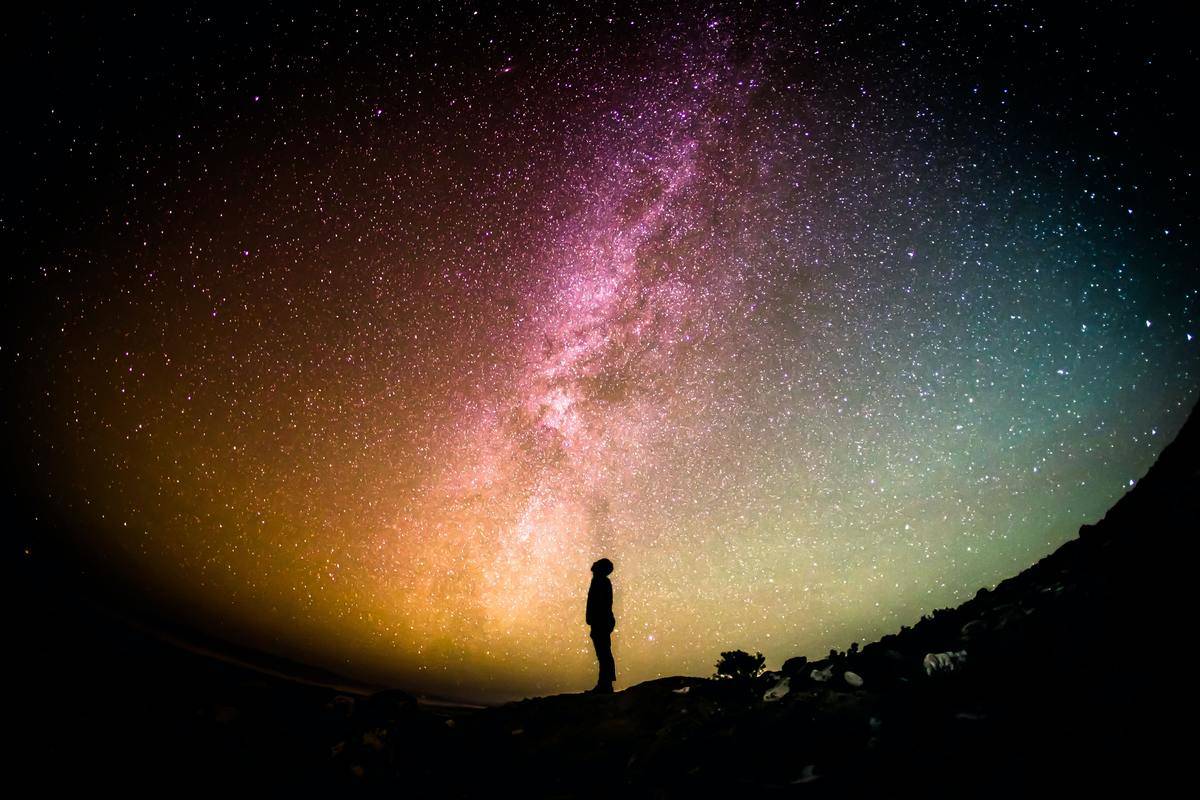 silhouette of a man standing coloful night under sky 