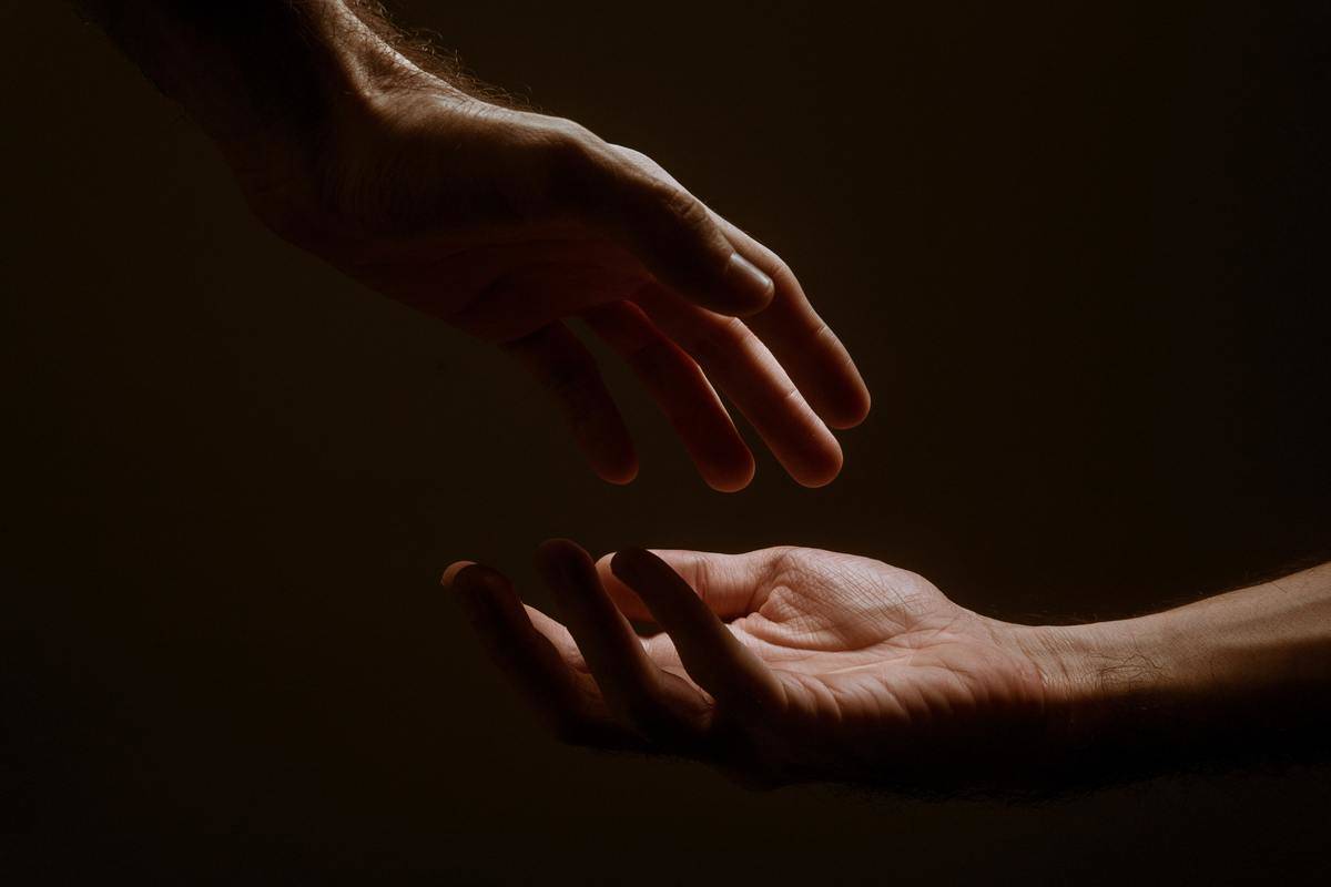 two hands reaching for each other over black background