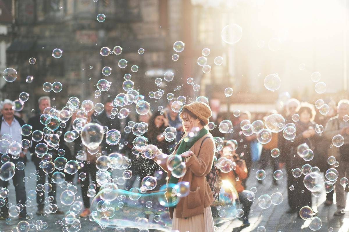 woman blows bubbles in the street by crowd