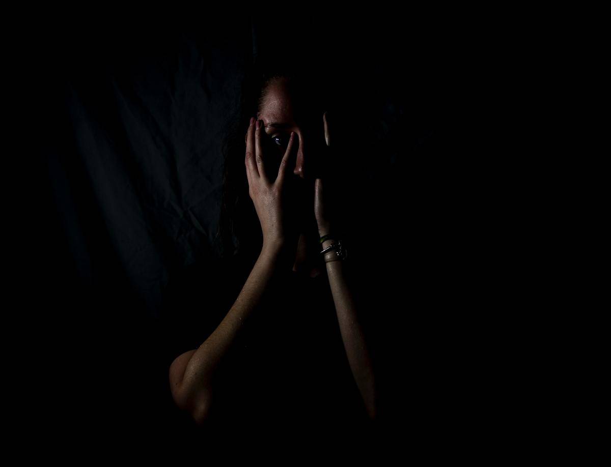 woman hiding her face by black background